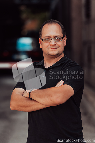 Image of A successful businessman with crossed arms, posing outdoors