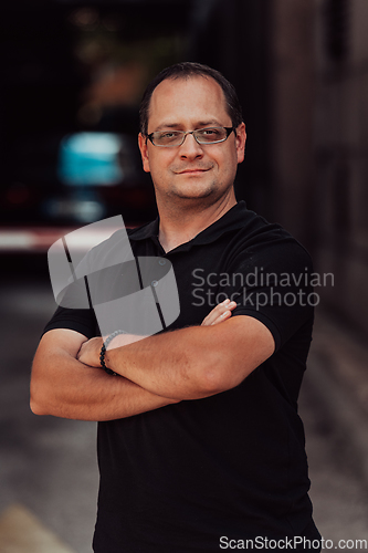 Image of A successful businessman with crossed arms, posing outdoors