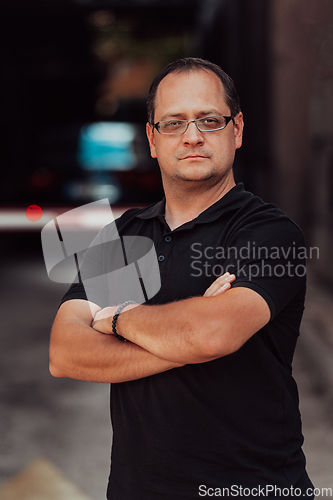 Image of A successful businessman with crossed arms, posing outdoors