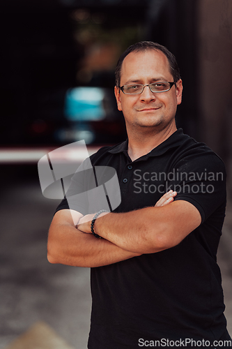 Image of A successful businessman with crossed arms, posing outdoors