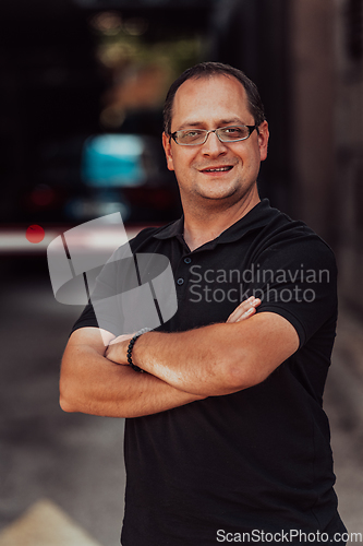 Image of A successful businessman with crossed arms, posing outdoors