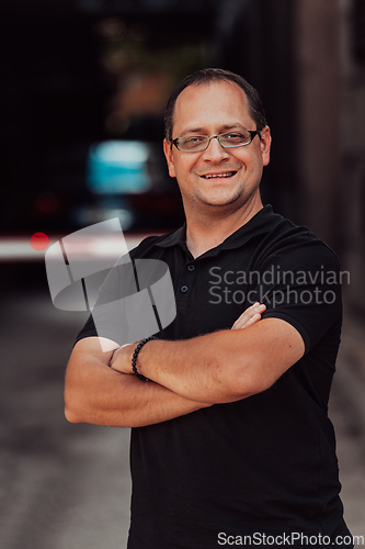 Image of A successful businessman with crossed arms, posing outdoors