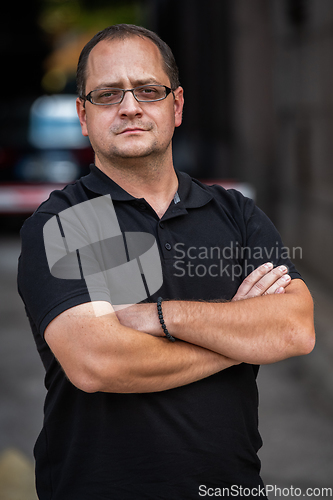 Image of A successful businessman with crossed arms, posing outdoors