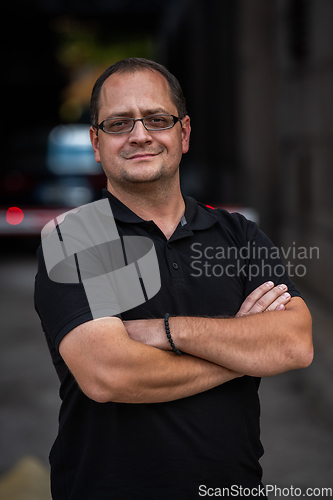 Image of A successful businessman with crossed arms, posing outdoors