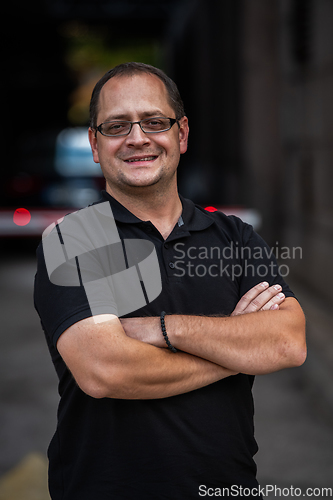 Image of A successful businessman with crossed arms, posing outdoors