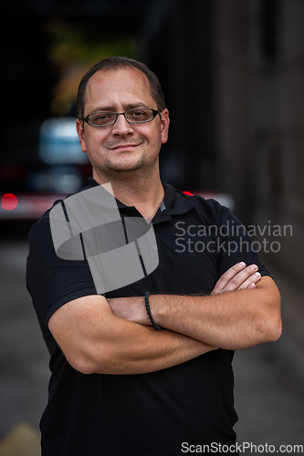 Image of A successful businessman with crossed arms, posing outdoors