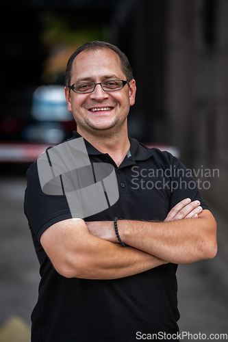 Image of A successful businessman with crossed arms, posing outdoors