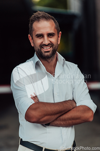 Image of A successful businessman in a white shirt with crossed arms posing outdoors