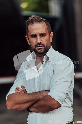 Image of A successful businessman in a white shirt with crossed arms posing outdoors