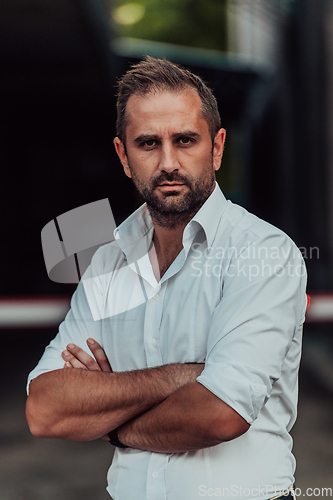 Image of A successful businessman in a white shirt with crossed arms posing outdoors