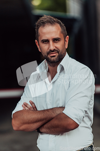 Image of A successful businessman in a white shirt with crossed arms posing outdoors