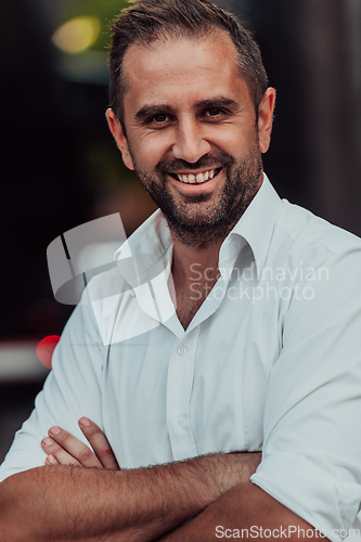 Image of A successful businessman in a white shirt with crossed arms posing outdoors