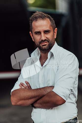 Image of A successful businessman in a white shirt with crossed arms posing outdoors