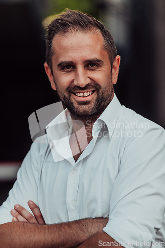 Image of A successful businessman in a white shirt with crossed arms posing outdoors