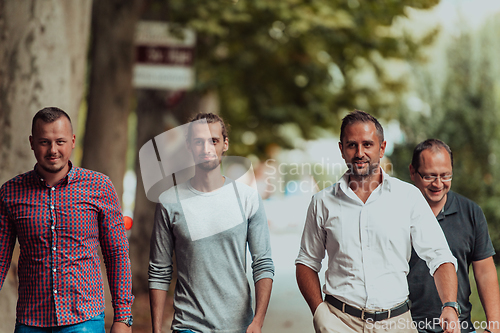 Image of After a productive day at work, a group of diverse colleagues enjoy a leisurely stroll through a modern and natural urban setting