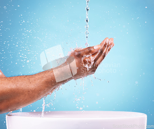 Image of Closeup, hands and water splash for cleaning, basin and dermatology against blue studio background. Zoom, man and washing with bowl, wellness and morning routine or grooming, skincare and backdrop