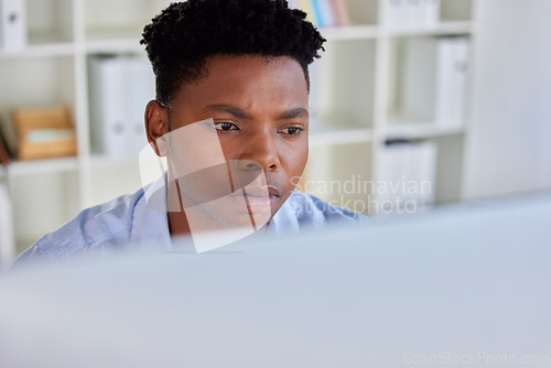 Image of Serious, black man and business analyst at a office computer reading digital data. Businessman, research and financial project planning of a startup employee working and thinking of web decision