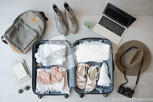 Image of Travel, suitcase and laptop with camera for vacation or holiday with online booking on floor. Above luggage, clothes and shoes while planning for summer photography journey motivation or inspiration