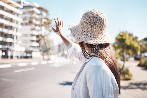 Image of Woman, city and street to stop taxi, travel and transportation in summer, holiday and outdoor urban adventure. Girl, back and hand sign for transport in metro, road or cbd for vacation in sunshine