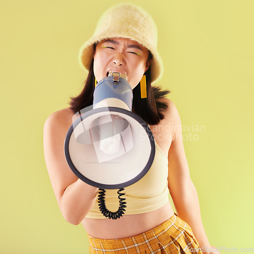 Image of Asian, woman and studio with megaphone for protest, speech and activism for human rights by background. Young gen z model, loudspeaker broadcast and yellow 90s aesthetic for change, justice and voice