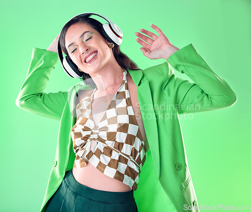 Image of Music, fashion and woman dance on green background with trendy, stylish clothes and cosmetics in studio. Disco aesthetic, headphones and happy girl relax, dancing and streaming song, audio and radio