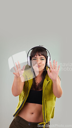 Image of Music, dance and portrait of woman with headphones in studio, happy and excited isolated on grey background. Streaming service, song and gen z fashion, girl dancing with hands up to online radio dj.