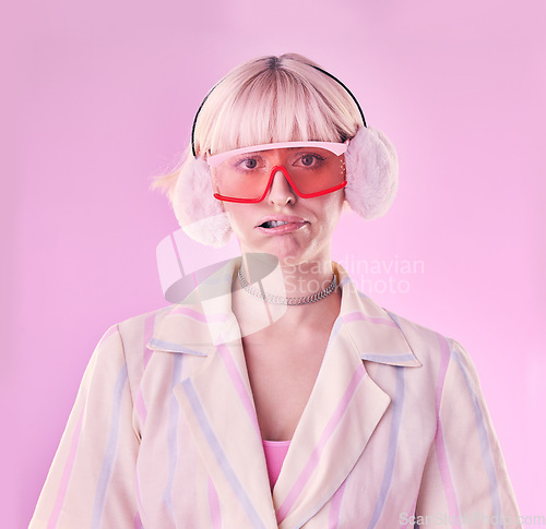 Image of Fashion, quirky and portrait of woman in studio for funny or comic face on pink background. Aesthetic model person with glasses and earmuffs for edgy vaporwave trend with creativity, humour and color