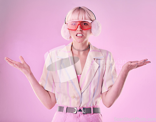 Image of Confused, angry and portrait of a woman with fashion isolated on a pink background in a studio. Anxiety, sad and stylish girl model wearing ear muffs while frustrated with anger and a problem