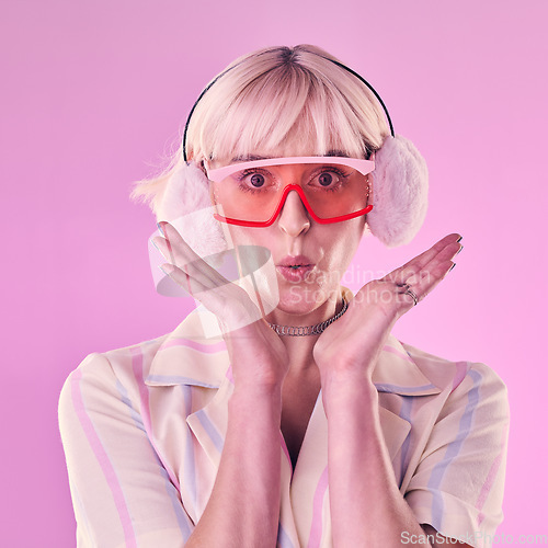 Image of Fashion, portrait and a woman quirky in studio for wow, surprise and comic face on pink background. Aesthetic model person with glasses and earmuffs for edgy vaporwave trend with creativity and color