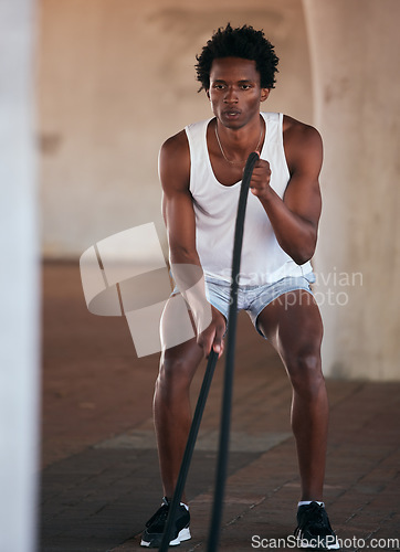 Image of Exercise, fitness and black man with battle ropes for training workout in the city outdoors. Sports, energy and male body builder or athlete with heavy rope for strength, power or health in street.