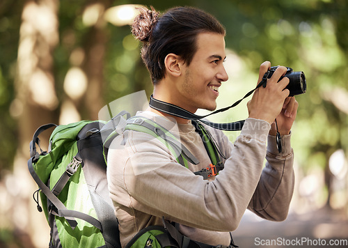 Image of Photographer man, camera and outdoor park with smile, focus or adventure with creative vision. Young nature journalist, photography expert and bird watching with tech, hiking or backpack for research