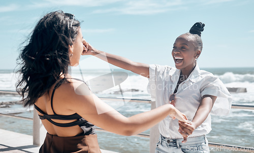 Image of Friends, holding hands and women dance at beach, having fun and laughing together outdoors. Comic, freedom and girls laugh at funny comedy or joke, dancing and enjoying time at promenade seashore.