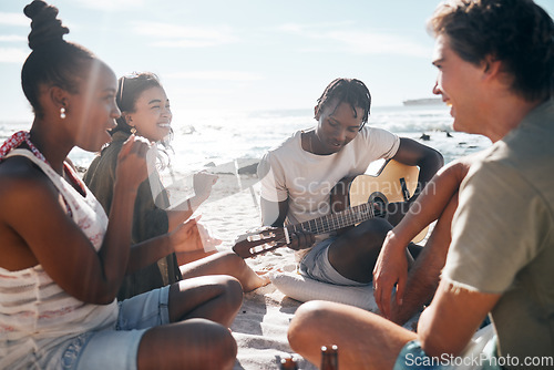 Image of Couple of friends, playing and guitar by beach, ocean or sea in holiday vacation, summer travel or social gathering. Smile, happy and bonding diversity people with musical instrument in relax picnic