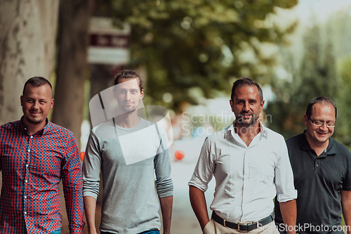 Image of After a productive day at work, a group of diverse colleagues enjoy a leisurely stroll through a modern and natural urban setting