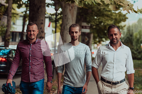 Image of After a productive day at work, a group of diverse colleagues enjoy a leisurely stroll through a modern and natural urban setting