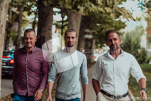 Image of After a productive day at work, a group of diverse colleagues enjoy a leisurely stroll through a modern and natural urban setting