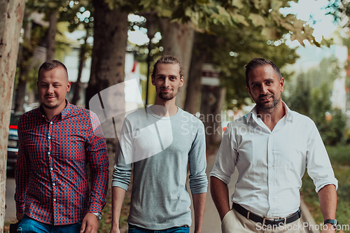 Image of After a productive day at work, a group of diverse colleagues enjoy a leisurely stroll through a modern and natural urban setting