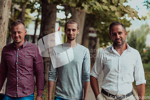 Image of After a productive day at work, a group of diverse colleagues enjoy a leisurely stroll through a modern and natural urban setting