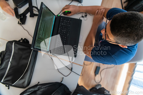 Image of Top view of programmer diligently testing smartphone applications while sitting in their office.