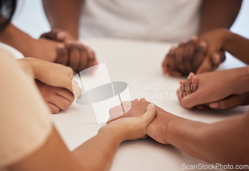 Image of Holding hands, praying and people worship for peace, trust or faith in God at a table together. Pray, Christian and community by group hand in prayer, praise or blessing while united in Jesus Christ