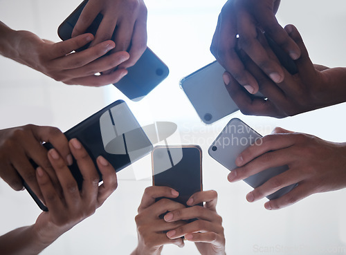 Image of Hands, phone and people networking below on social media, mobile app or chatting together. Low angle hand of group with smartphone in circle for online network share, data sync or team communication