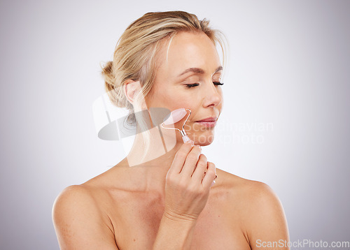 Image of Beauty, face roller and woman doing massage in studio with dermatology and cosmetic tools. Mature aesthetic model skin care facial product for health, wellness and natural skin or anti aging glow