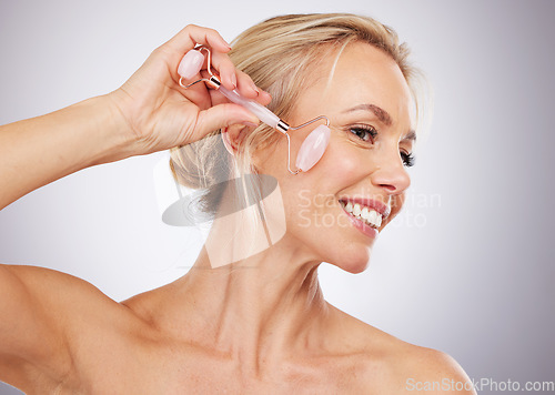 Image of Facial roller, beauty and woman doing massage in studio with dermatology and cosmetic tools. Mature aesthetic model skincare face product for health, wellness and natural skin or anti aging glow