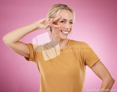 Image of Woman, peace and portrait on pink background, smile and studio pose. Happy female face, v sign and hands emoji of cool lady model for victory, winking and fun mood with happiness, review and success