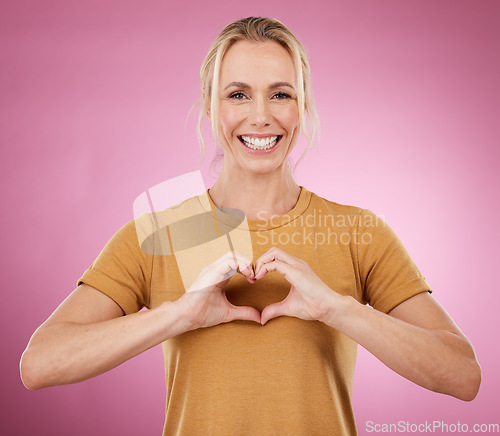 Image of Heart, hands and portrait of woman on pink background, studio and color backdrop with emoji, care and kindness. Happy female model with finger shape for love, thank you and smile in support of peace