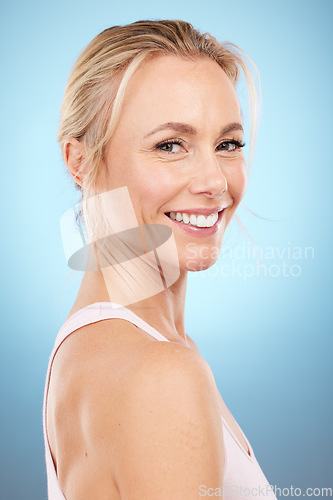 Image of Skincare, woman and portrait in studio for beauty, dermatology and wellness cosmetics on blue background. Happy mature female model, facial and smile for aesthetic glow, botox transformation and face