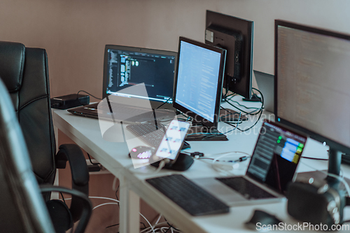 Image of Computer screens running programming code in empty software developing agency office and computers parsing data algorithms in background. Neural network servers cloud computing in data room.