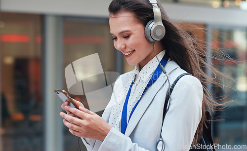 Image of Business, woman in city and smartphone with headphones, smile or walking in town, streaming music or radio. Female professional, consultant or agent outdoor, cellphone or headset for podcast or urban