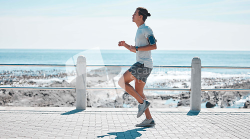 Image of Fitness, sports and man running by ocean in action for wellness, performance and athlete endurance. Nature, motivation and male runner by sea for exercise jog, marathon training and cardio workout