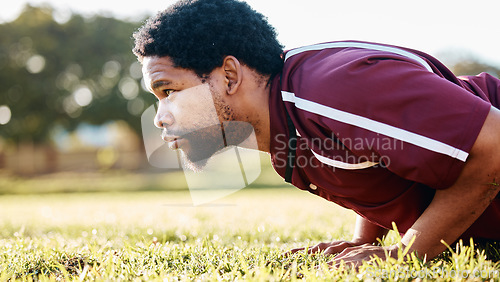 Image of Sports, workout and man doing a push up on the field for training or practice before a game. Fitness, health and African male athlete doing a warm up exercise before a match by a grass stadium.
